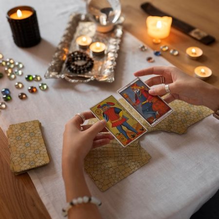 Mãos abrindo cartas de tarot sobre a mesa