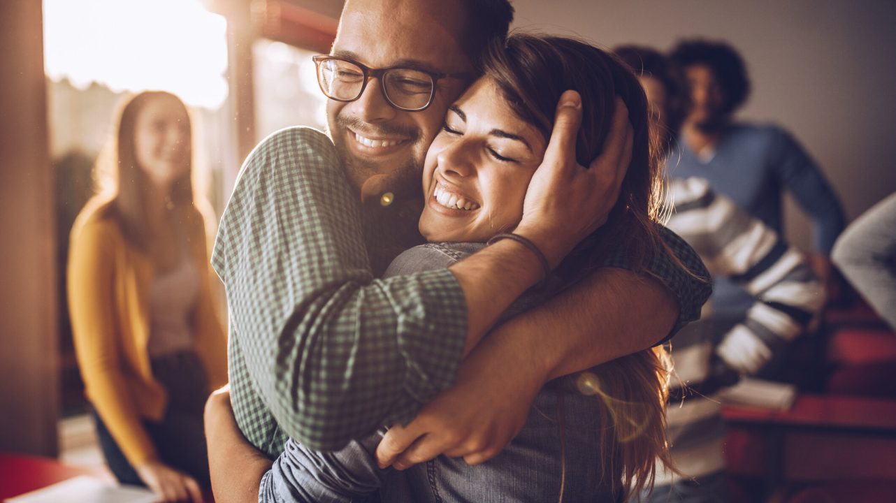 Happy college couple embracing with great affection on a class at lecture hall.